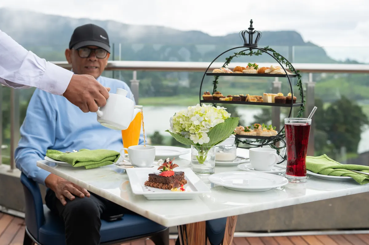 High Tea at the Dome: a tiered afternoon-tea stand on a marble terrace table overlooking the misty lake and hills