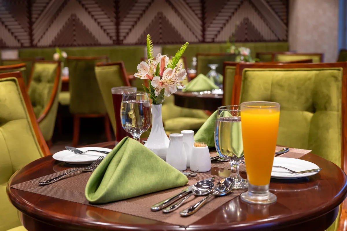Windrose Restaurant: warmly lit tables and upholstered chairs beneath a timber ceiling, opening to the highland view beyond