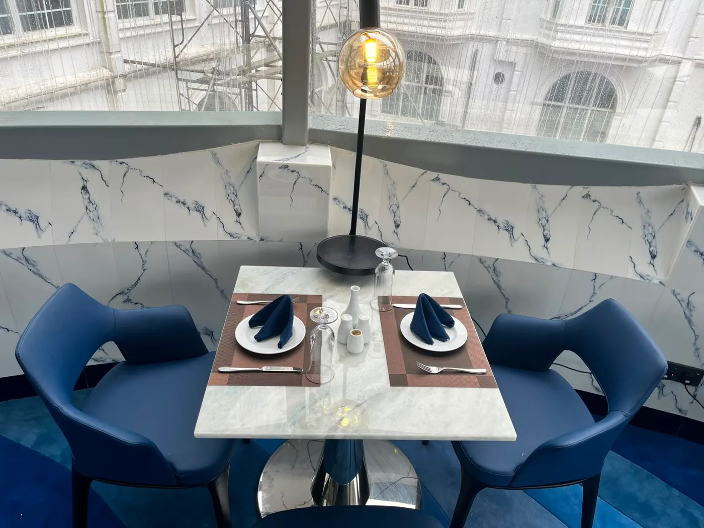 A marble table for two set against the veined wall of The Eye