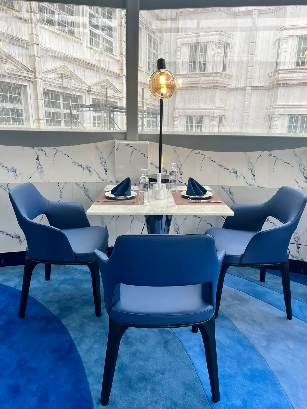 Navy leather chairs around a marble table beneath a globe lamp in The Eye
