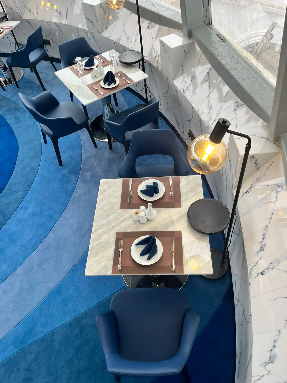 Tables of The Eye seen from above, set with navy napkins and silver