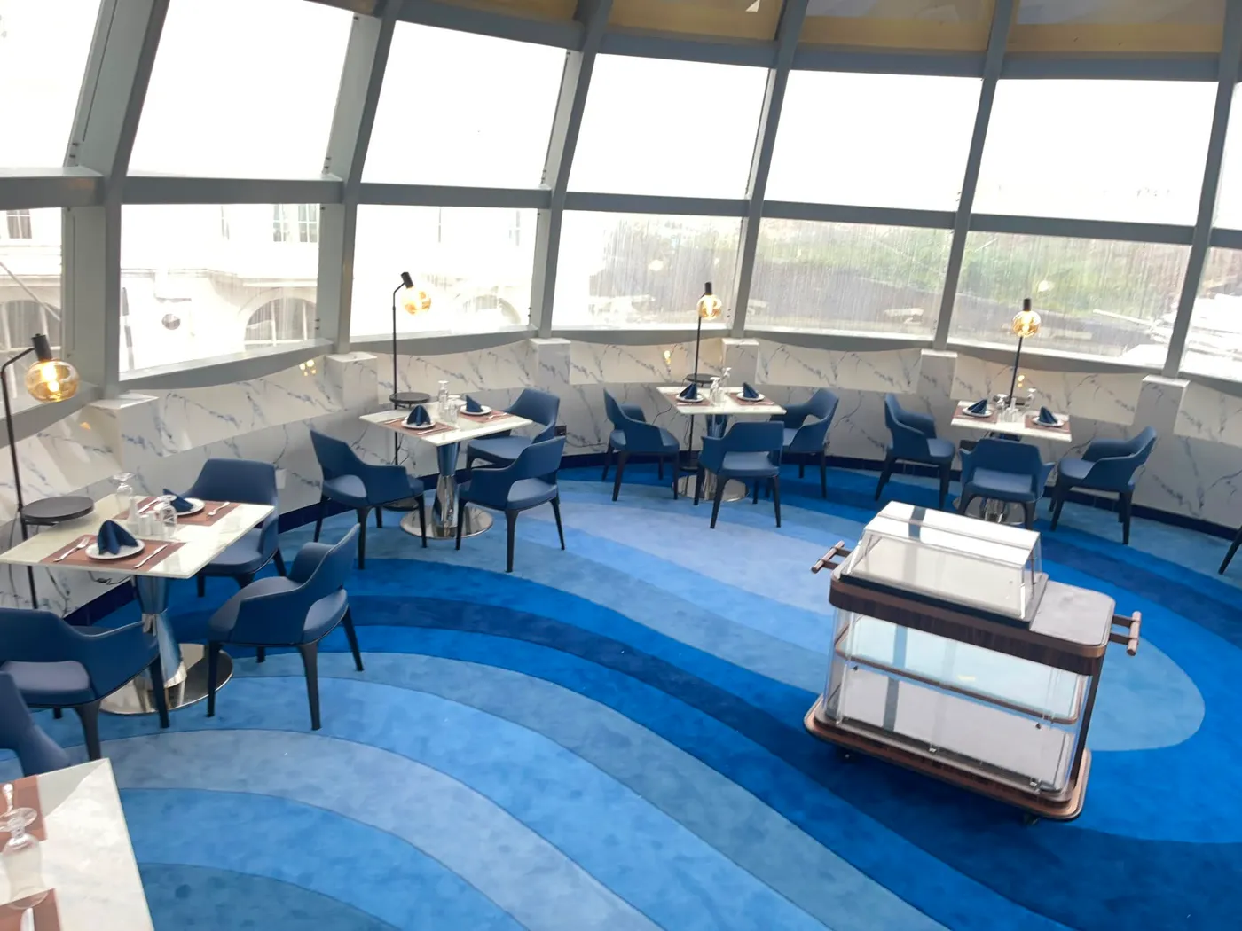 The Eye dining floor beneath the glass dome, its carpet swirling in waves of blue
