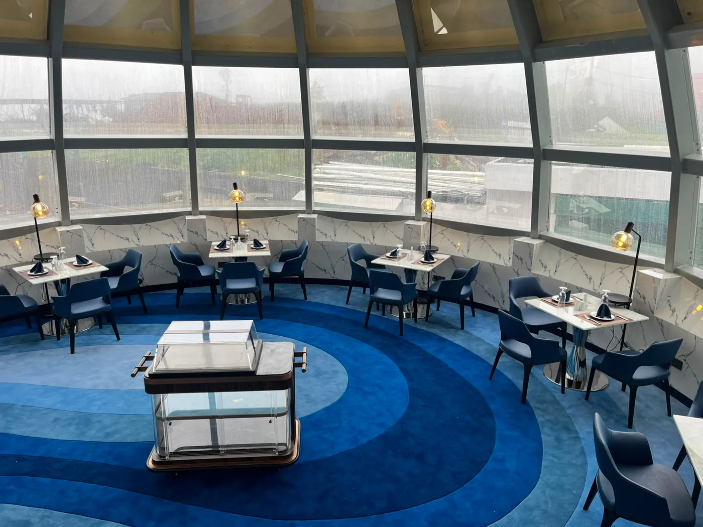 Sapphire chairs and marble tables ringing the wave-patterned carpet of The Eye