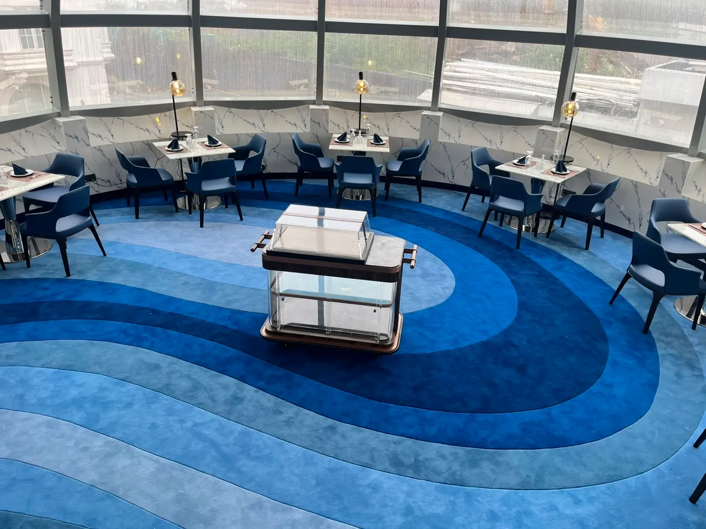 Tables in The Eye framed by the dome glazing and the hotel facade beyond