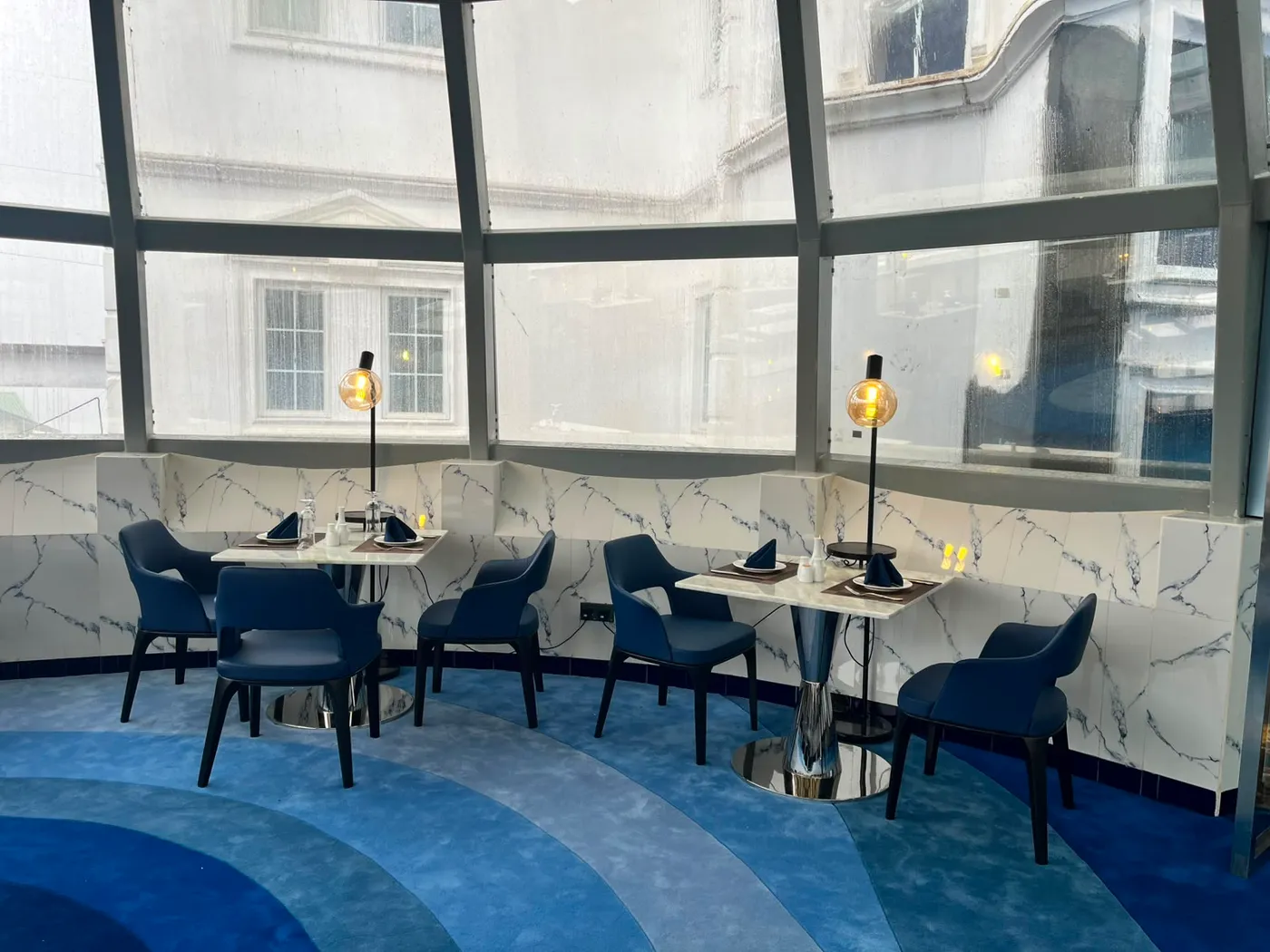 A quiet corner of The Eye with amber globe lamps over marble tables
