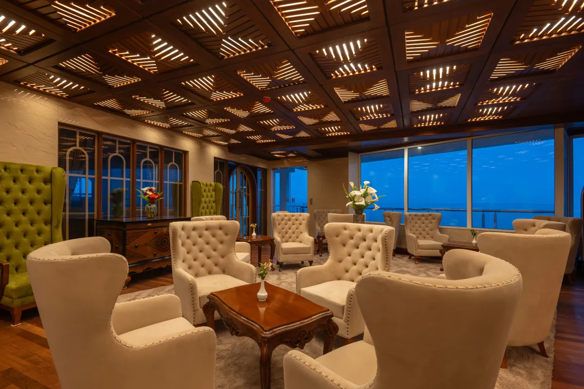 The Horton Heights lounge: tufted cream armchairs gathered beneath a coffered timber ceiling, framed by tall highland-view windows