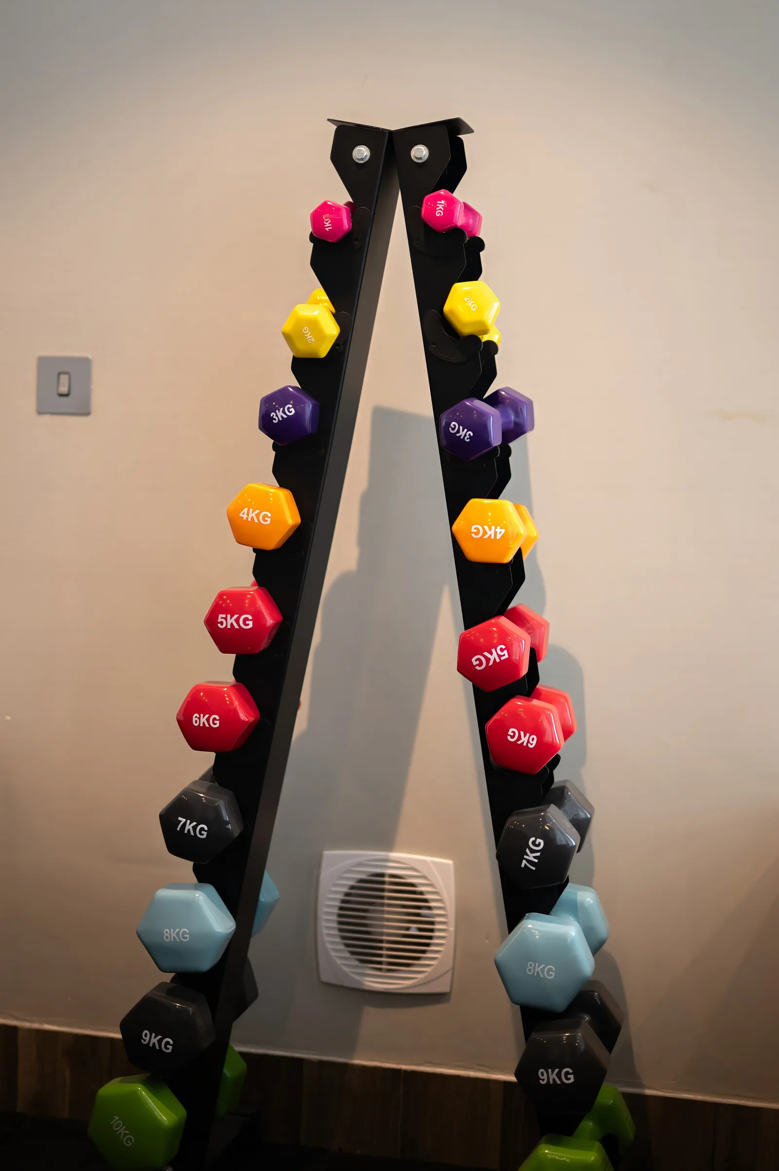 A-frame rack of colour-coded vinyl hand weights from one to ten kilograms
