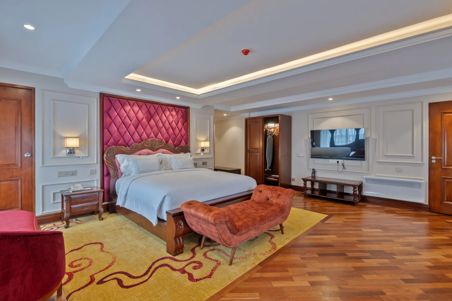 The Executive Suite at Horton Heights with a crimson tufted headboard beneath a cove-lit ceiling